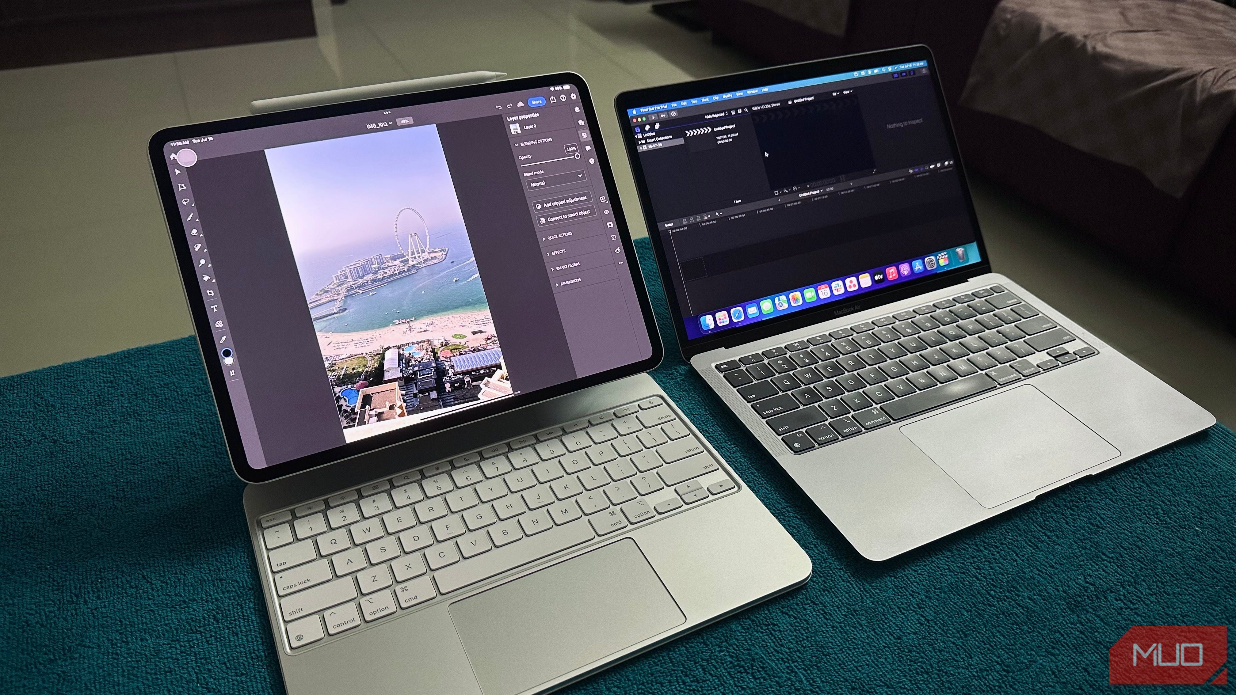 An iPad Pro running Photoshop next to a MacBook running Final Cut Pro on a desk