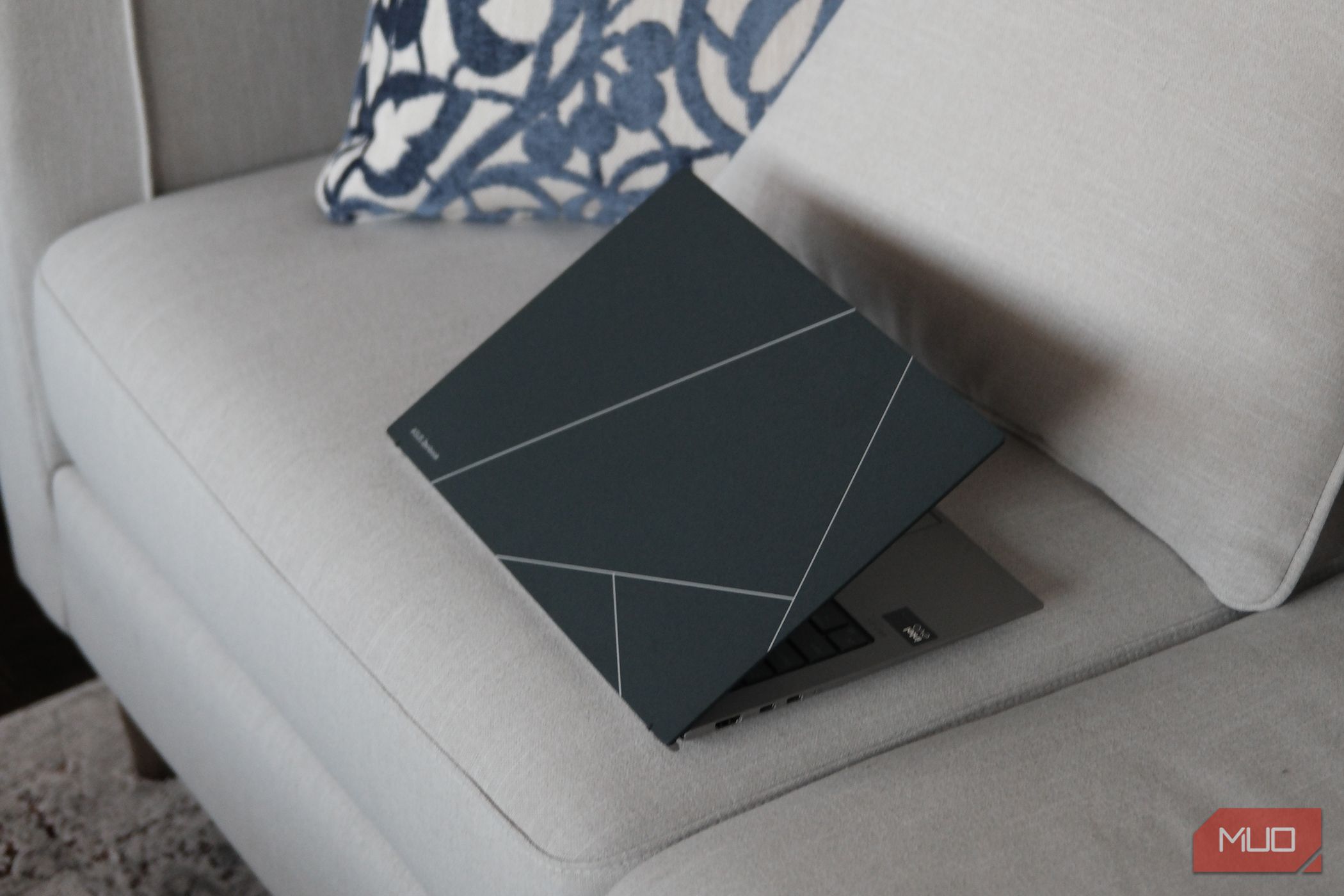 ASUS Zenbook S 13 OLED ligeiramente aberto em um sofá