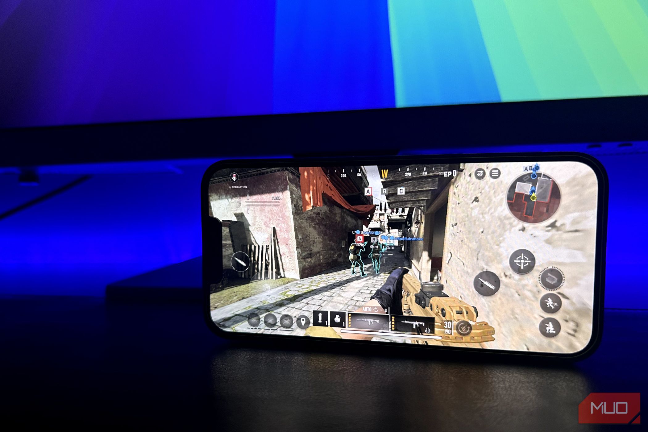 آیفون با اجرای Call of Duty: Warzone Mobile با مانیتور در پس‌زمینه