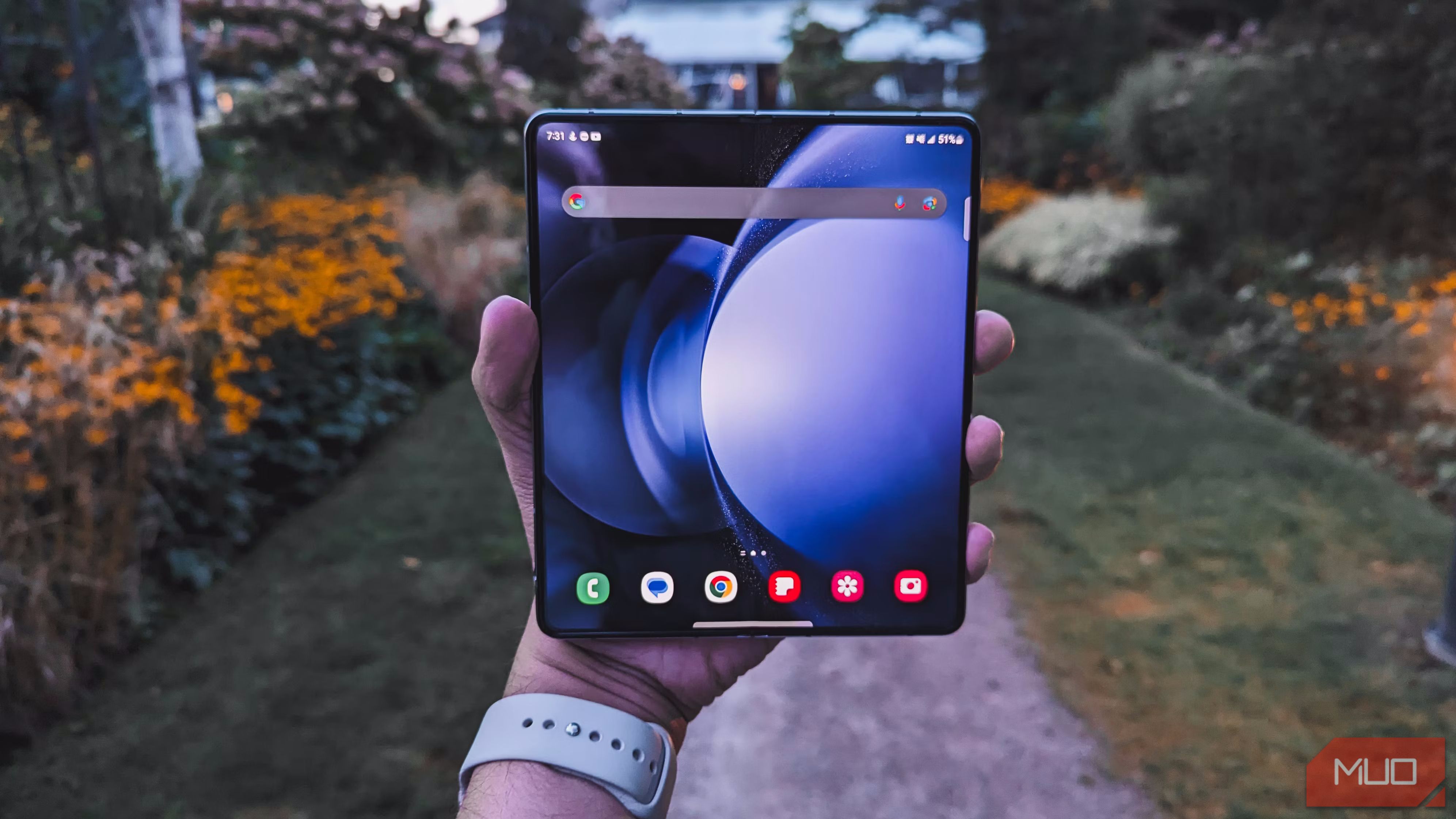 A man holding a Galaxy Z Fold 5 with a garden in the background