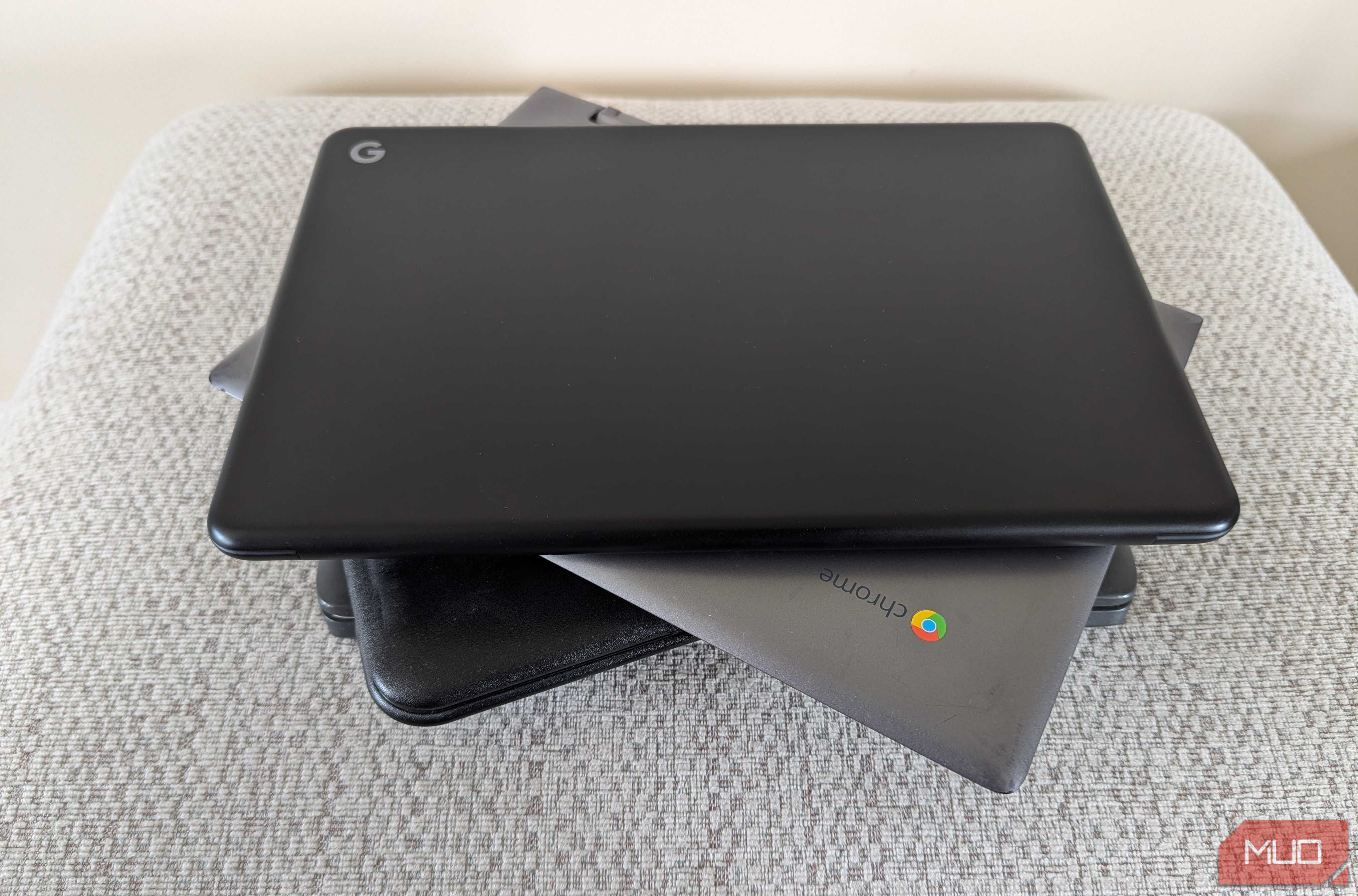 Several Chromebooks stacked in a pile on a footstool