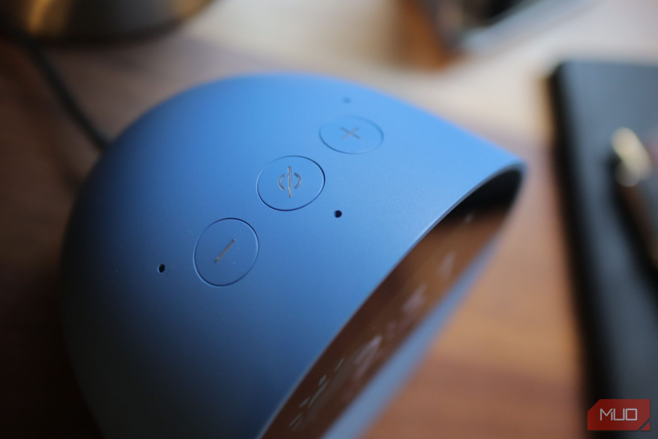 Echo Spot Volume and mute buttons in a top down view on a brown night table. 