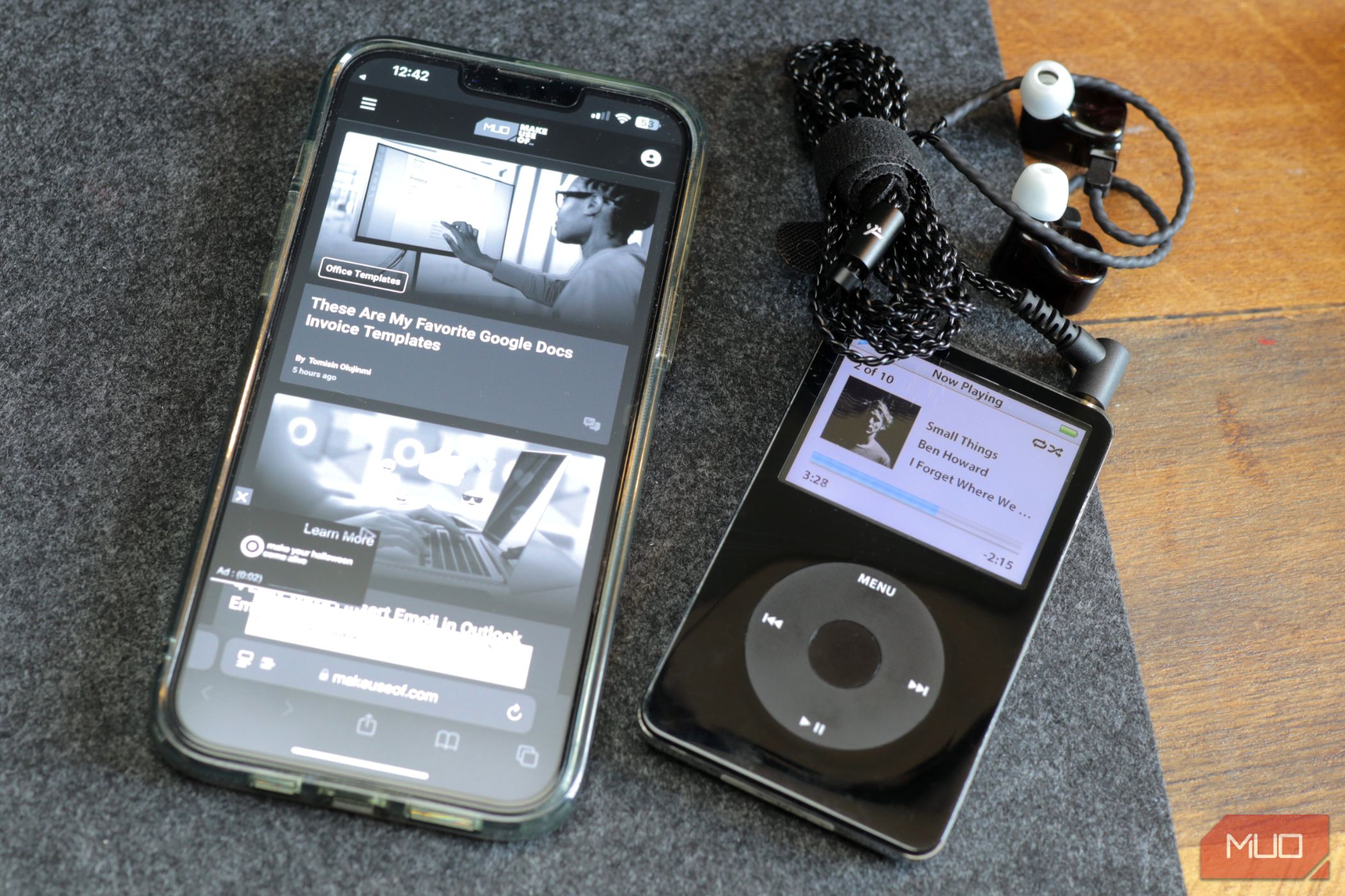 A black iPod and grayscale iPhone 13 on a felt desk pad 