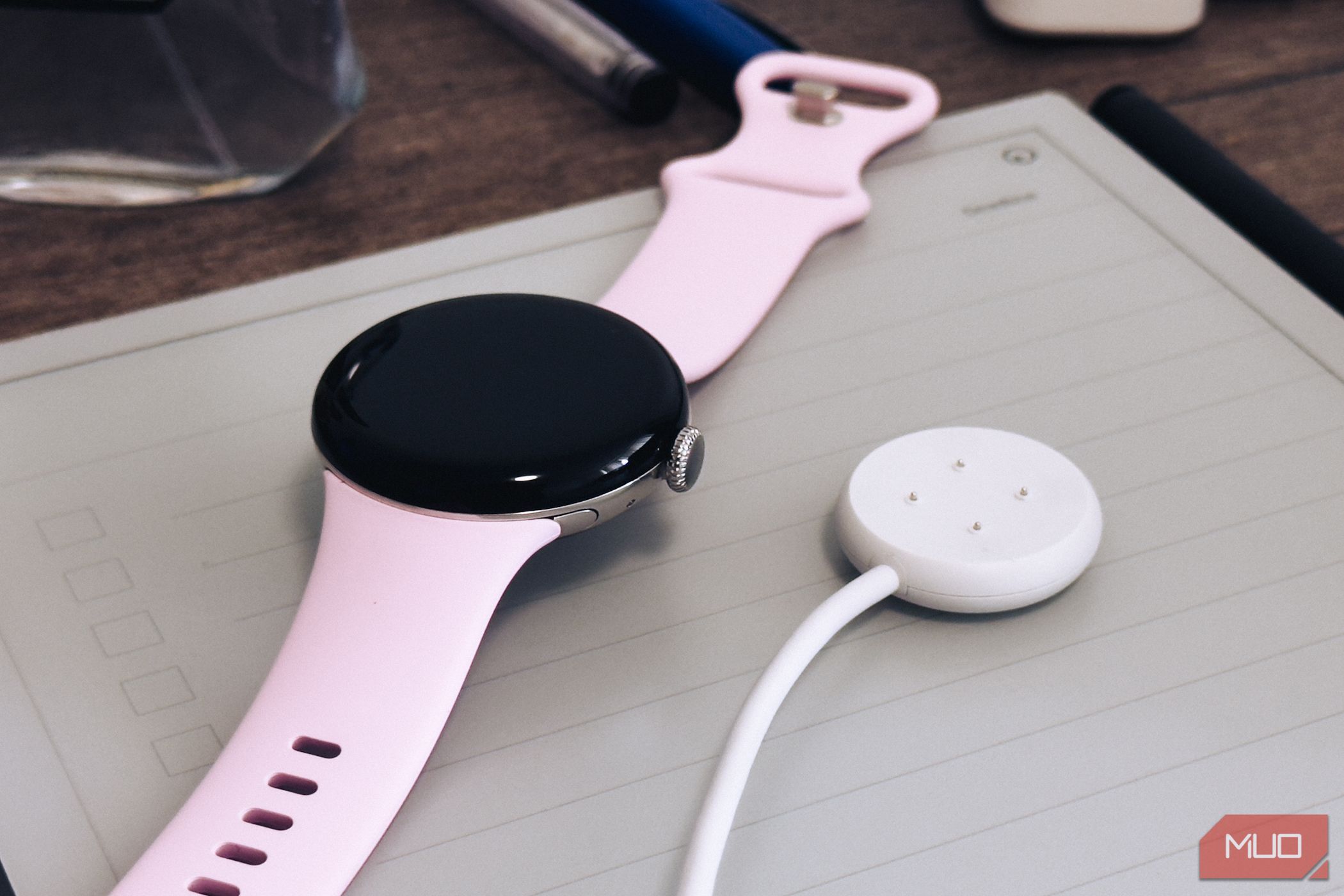 Google Pixel Watch 3 charging puck on table next to the watch