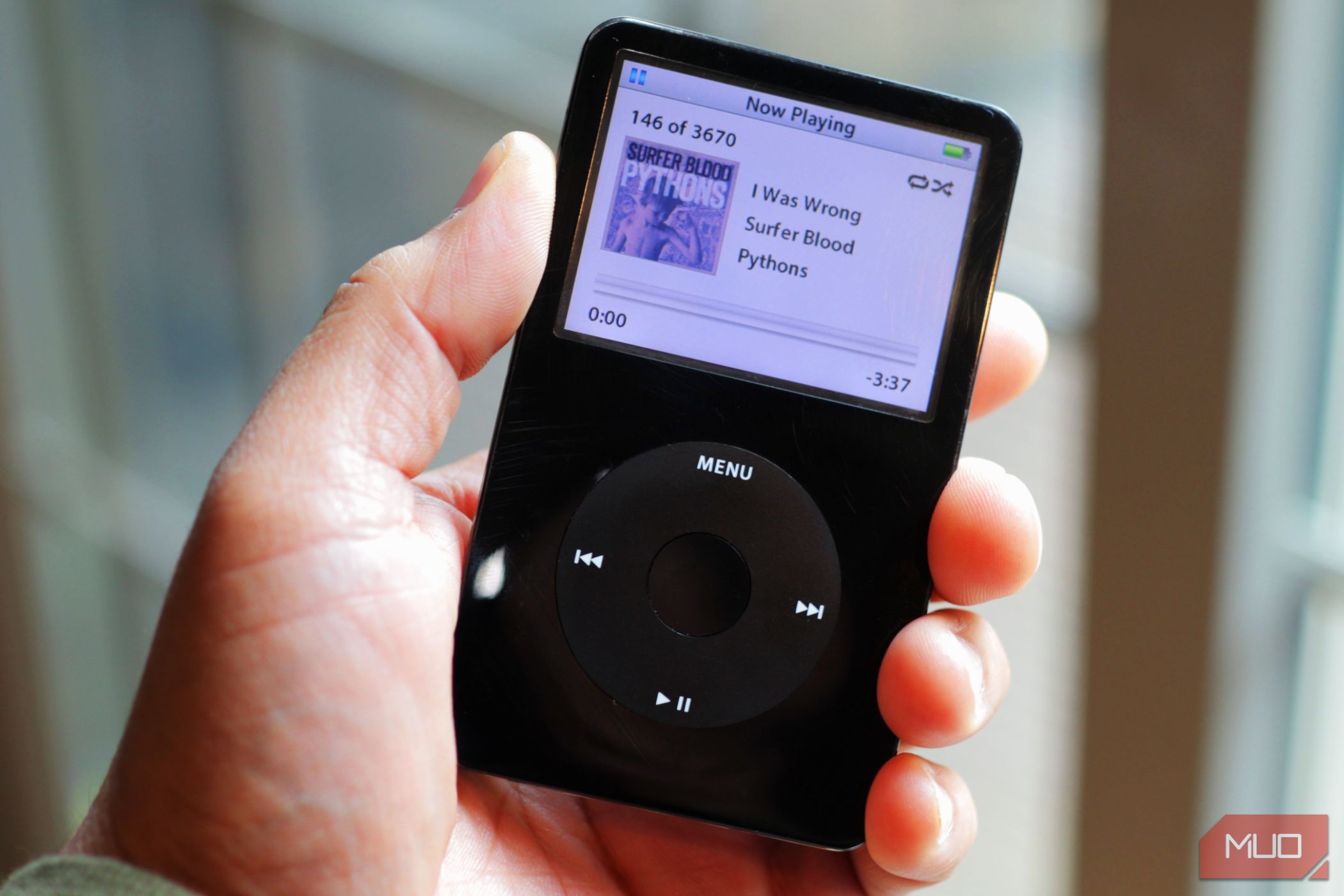 Black iPod classic held in hand near the window