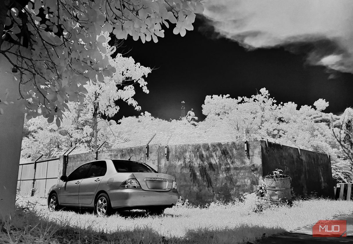 Monochrome infrared image of a parked car and trees