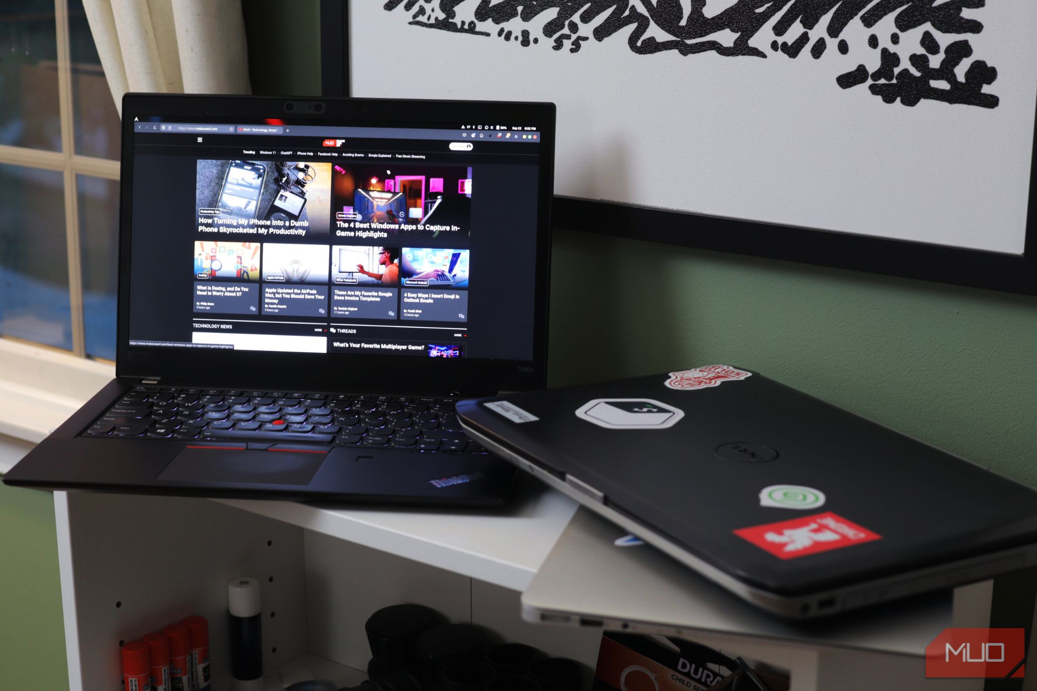 Two laptops on a white shelf with one opened to MakeUseOf