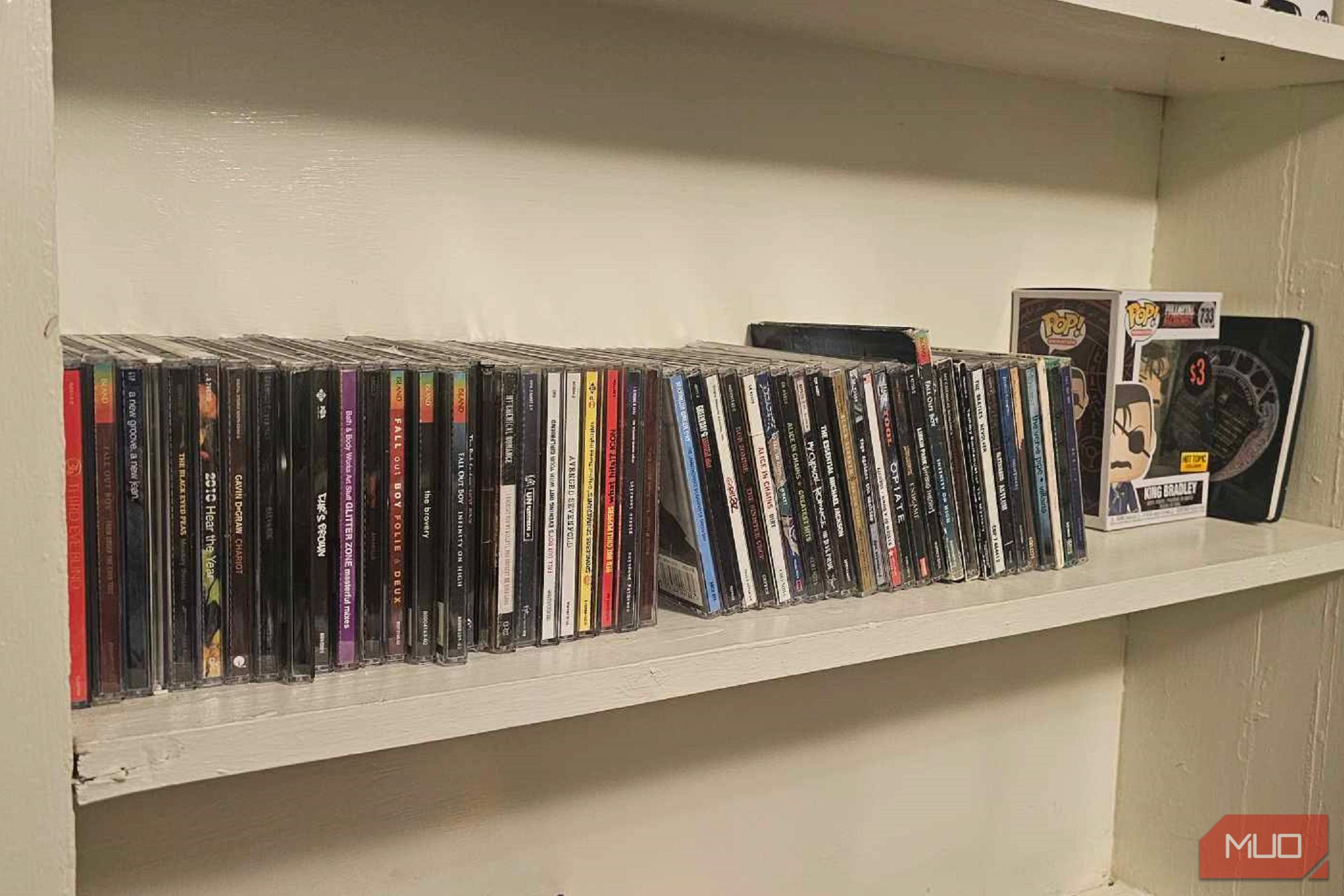 a row of cds on a shelf, next to a funko pop and notebook