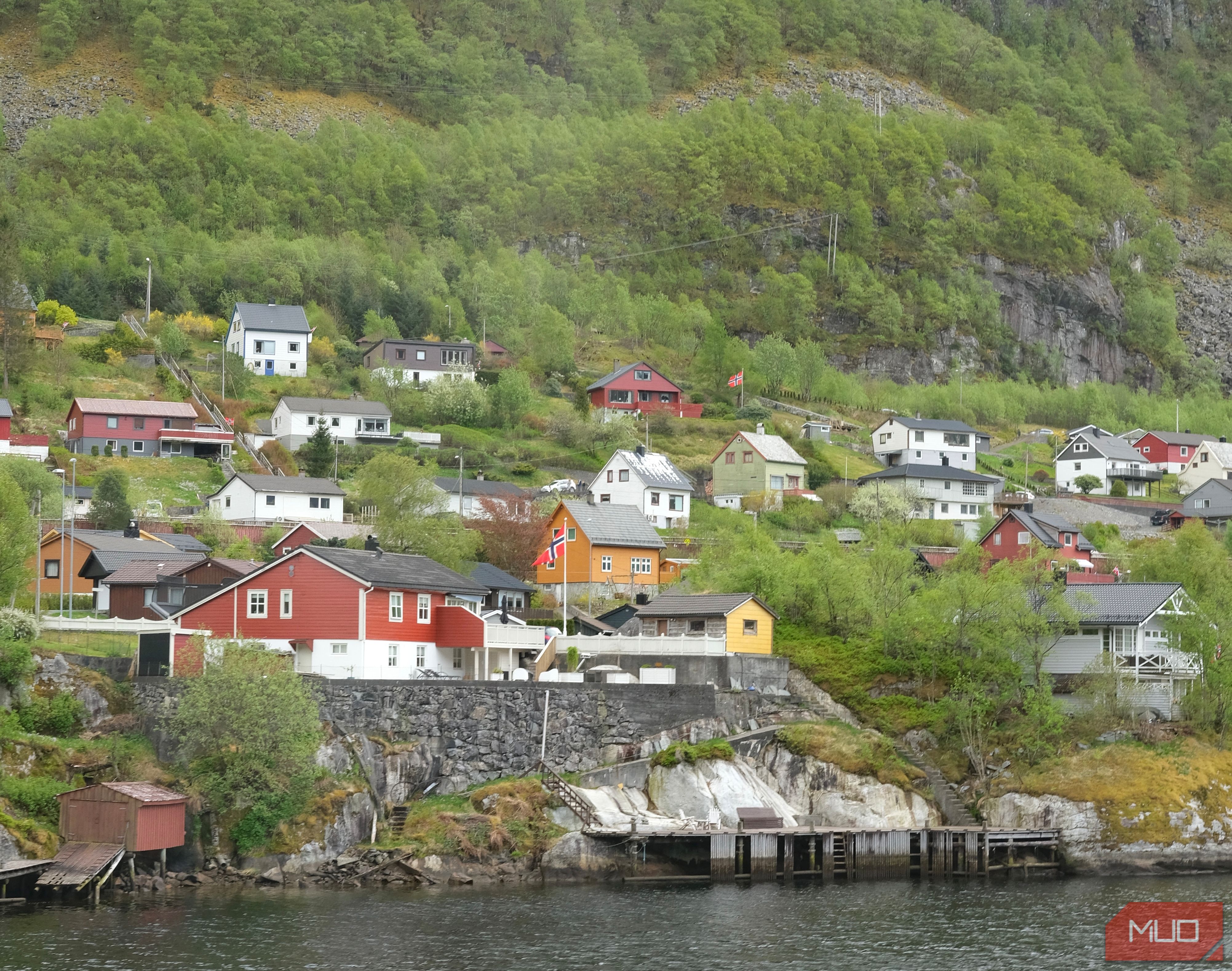 A photo of some houses next to the water with a mountain behind them