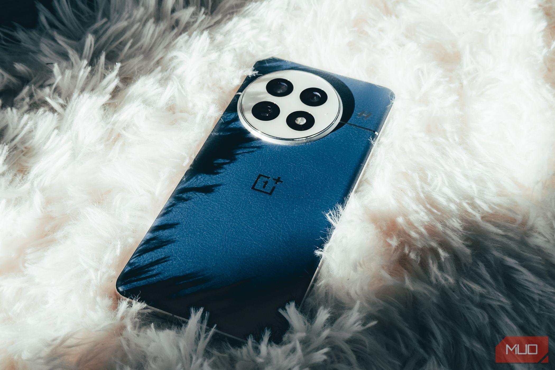 OnePlus 13 on a fluffy white carpet.