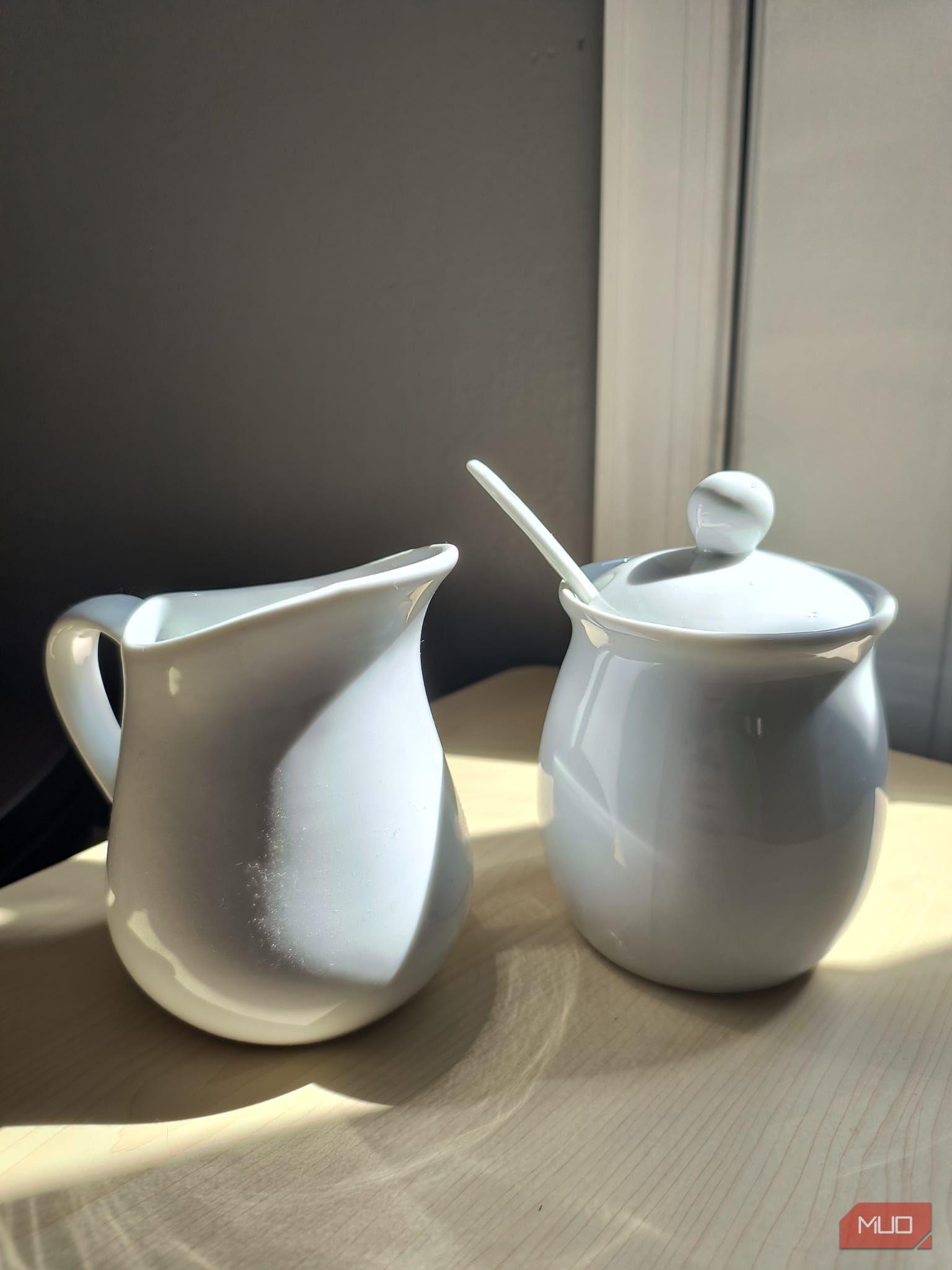 A white ceramic sugar and cream set sitting in direct sunlight—HDR enabled