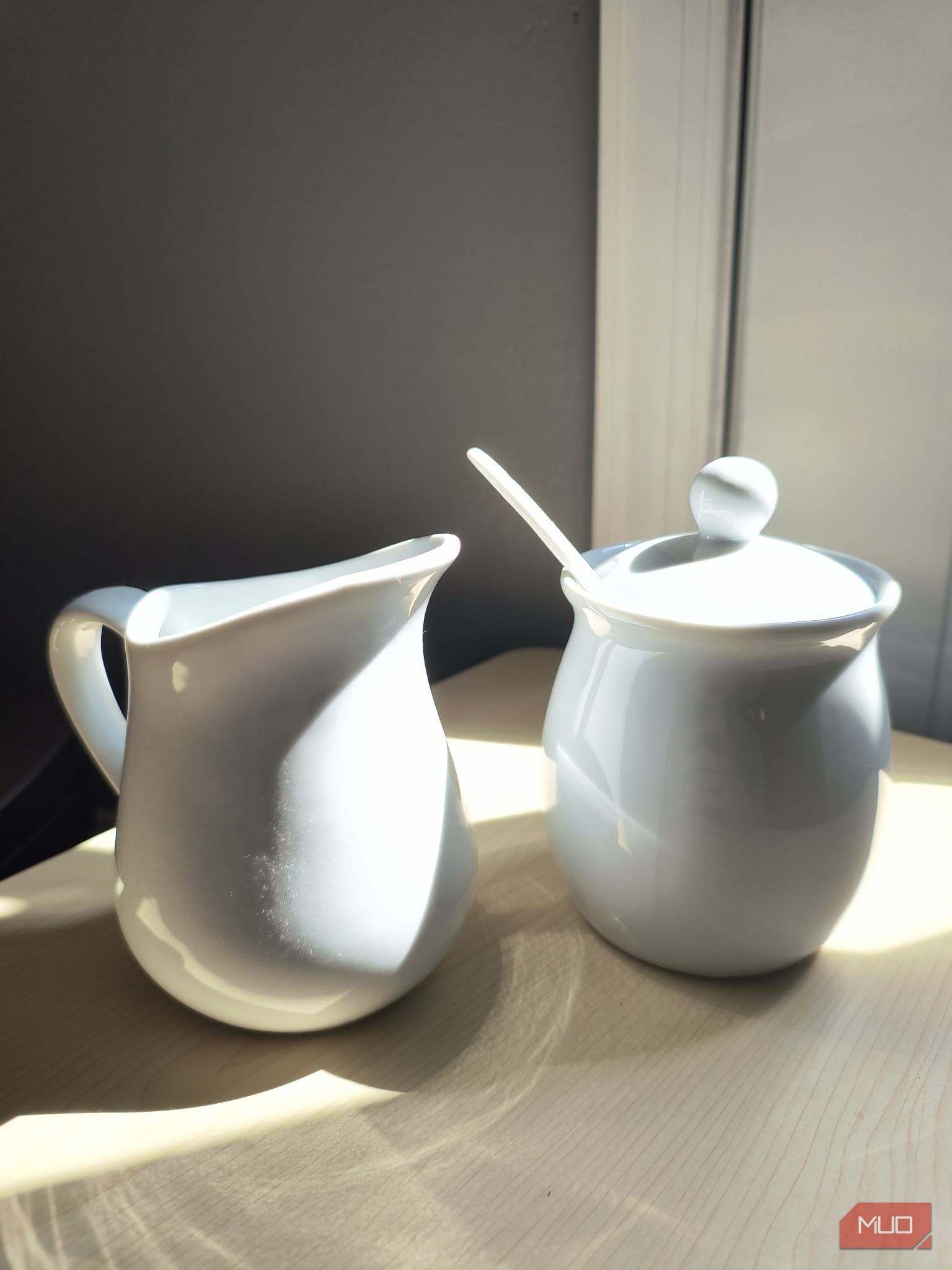 A white ceramic sugar and cream set sitting in direct sunlight—HDR disabled