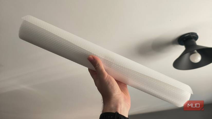 A hand holding up a plastic liner roll