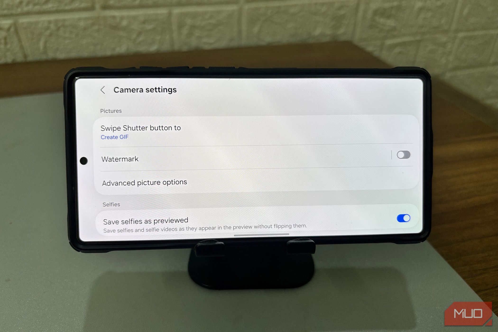 A Samsung phone is on a holder showing the camera settings