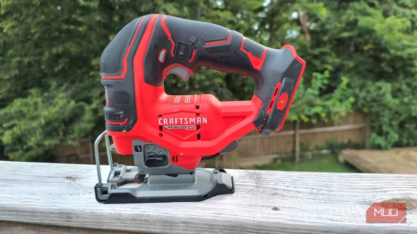 A cordless jigsaw sitting on a wooden rail