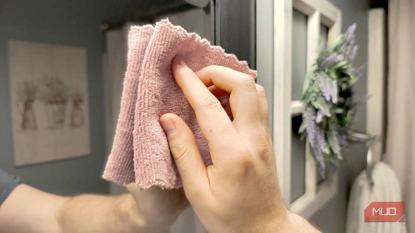 A hand using a microfiber cloth to clean a mirror