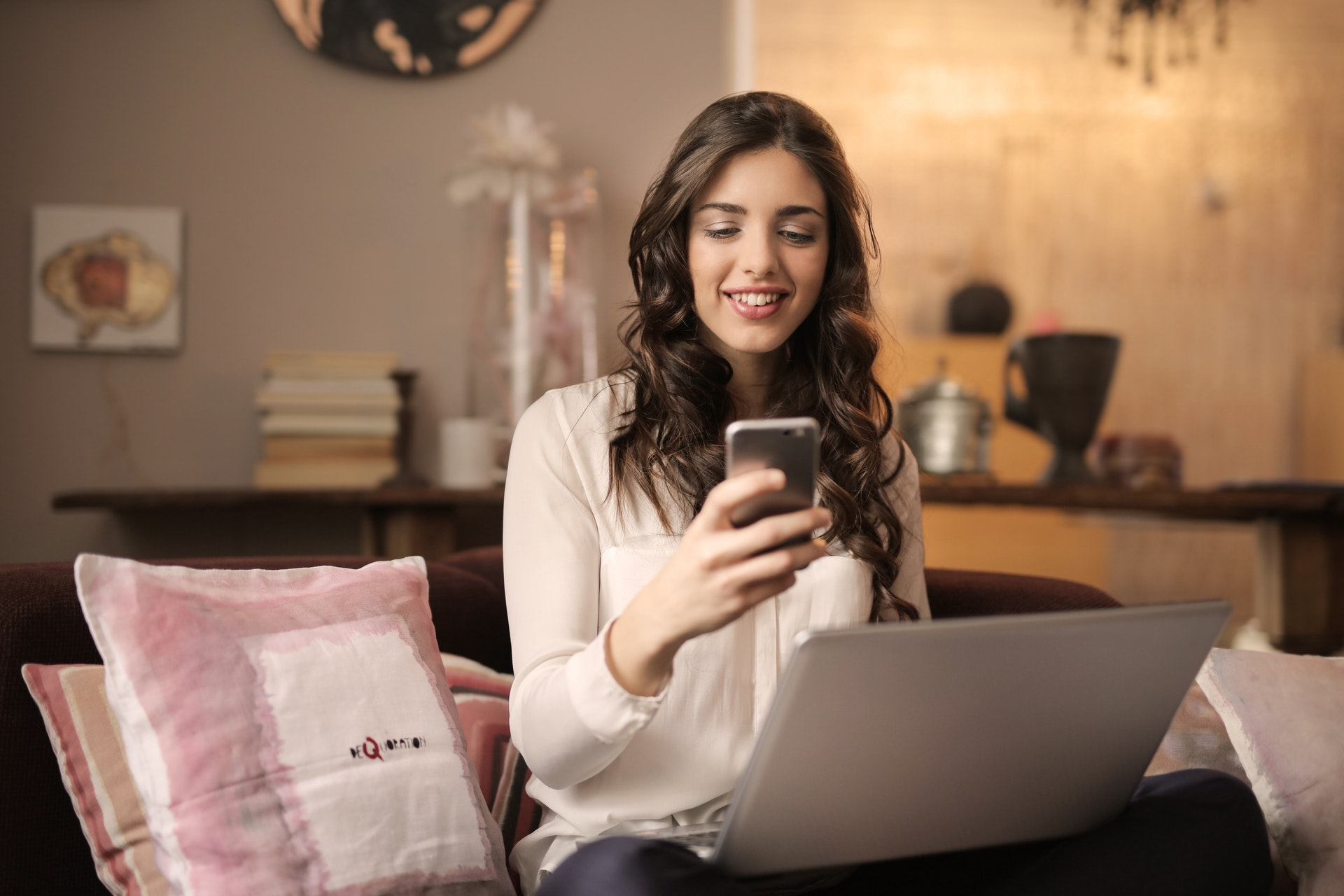 So schützen Sie sich vor betrügerischen Geschäften bei Shopify - Woman smiling at phone with laptop