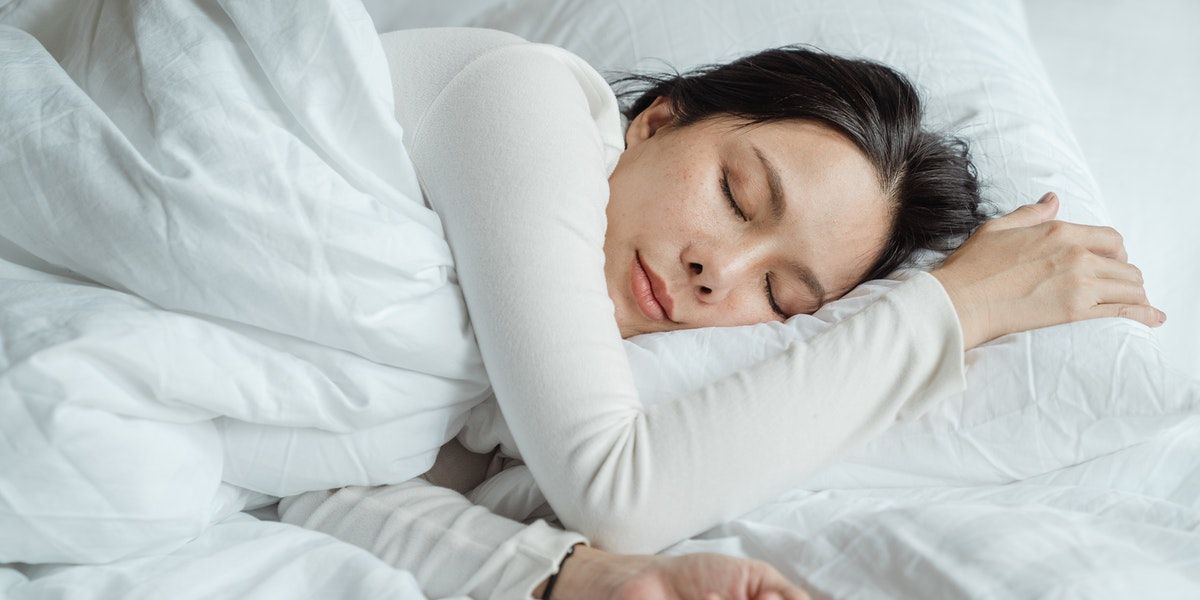 Woman Sleeping in White Sheets with Phone - 10 consigli per evitare di rompere il tuo smartphone
